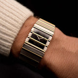 Gold Vintage Piaget Polo 7131 Onyx Zebra watch from the 1980s on a wrist with a dark background. 25mm wide, 18k white/yellow gold with Flawless Onyx and Zebra Dial, Gold bracelet.