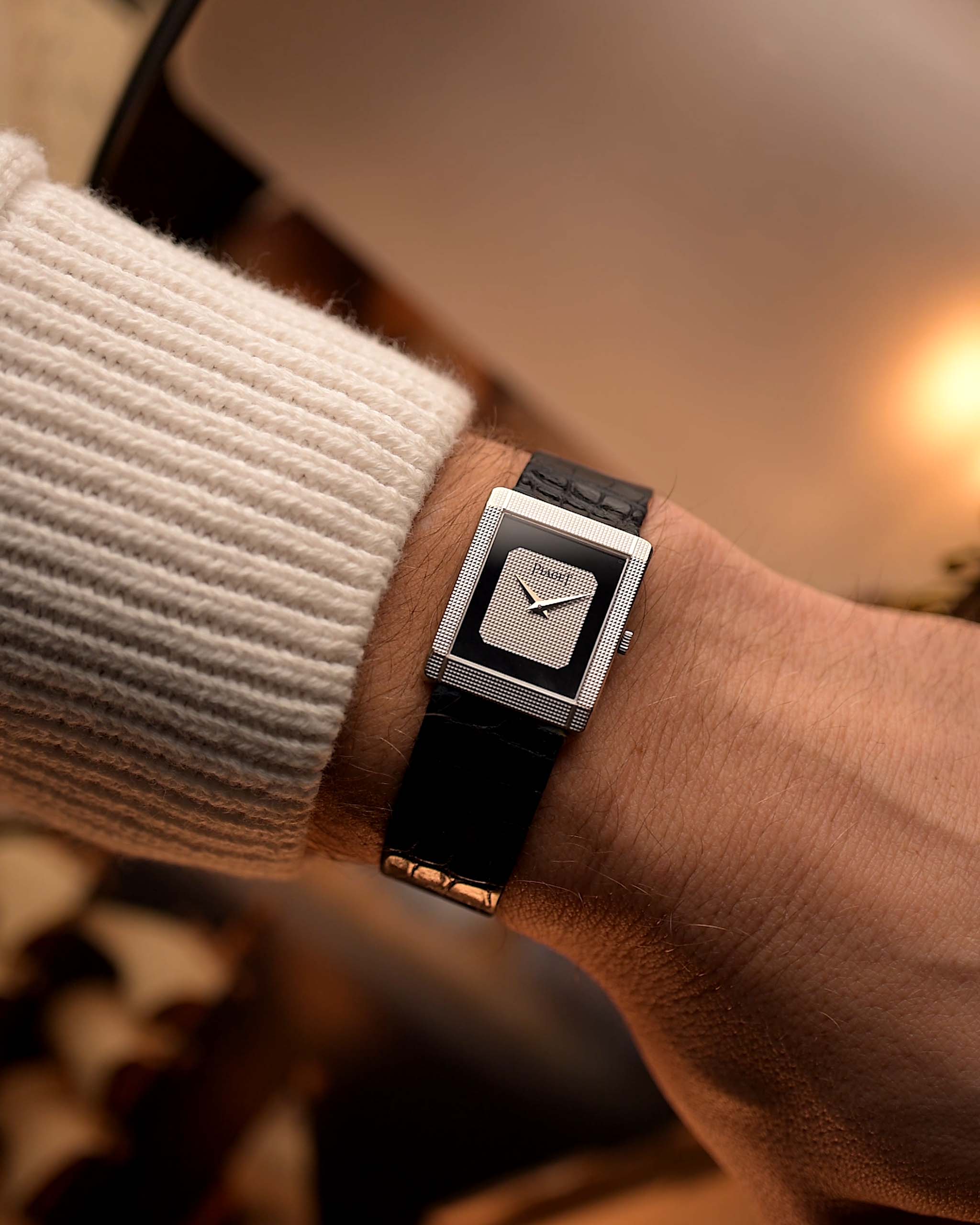 Vintage Piaget Protocole 9151 watch, 18k white gold, Onyx dial, tank shape, Caliber 9P movement, leather strap, on a wrist, blurred background