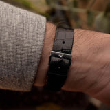 Close-up of a Vintage Piaget Protocole 9151 watch leather strap, 18k white gold, Onyx dial, tank shape, Caliber 9P movement, leather strap, on a wrist, blurred background