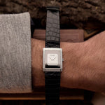 Vintage Piaget Protocole 9151 watch, 18k white gold, Onyx dial, tank shape, Caliber 9P movement, leather strap, on a wrist, with a blurred background