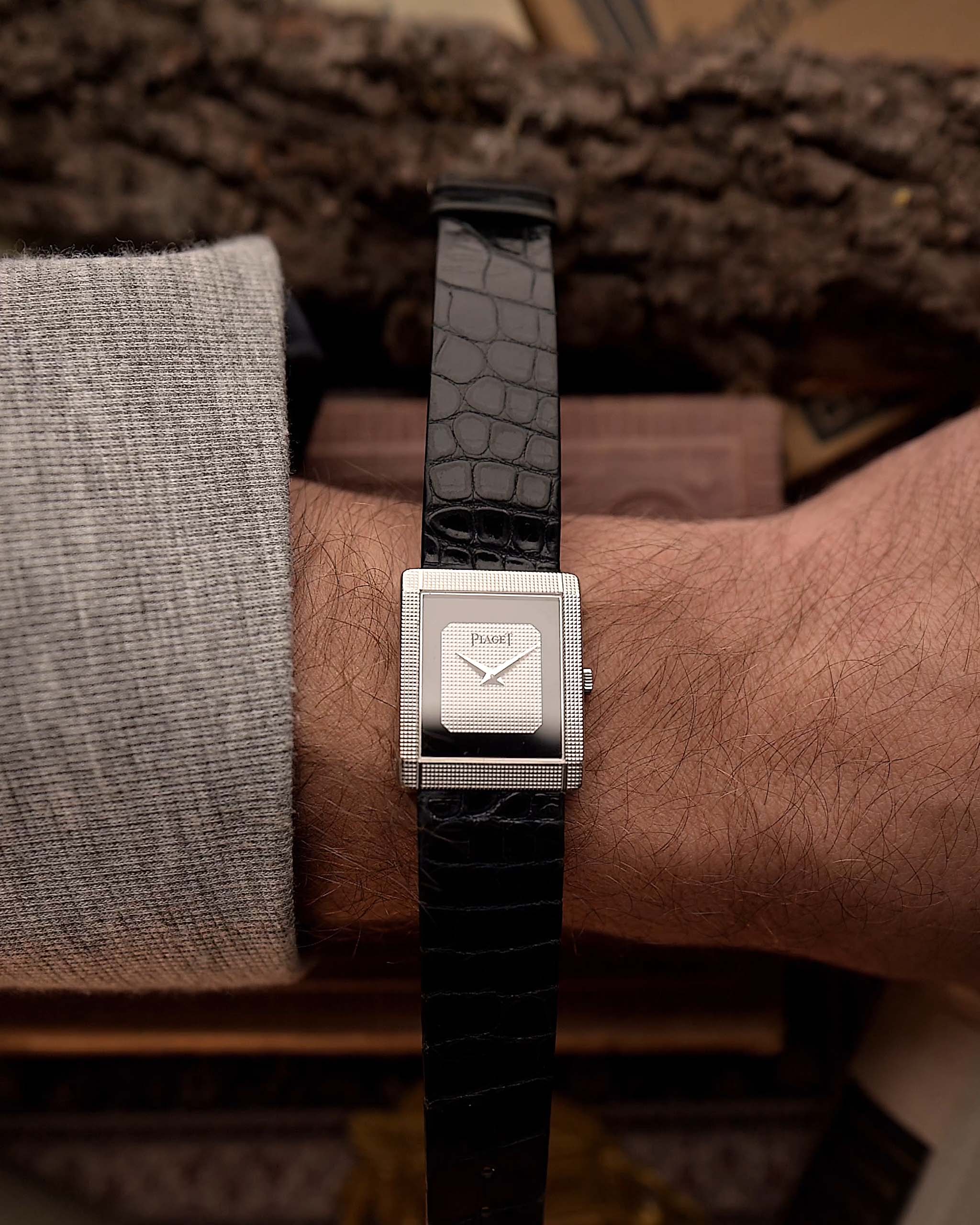 Vintage Piaget Protocole 9151 watch, 18k white gold, Onyx dial, tank shape, Caliber 9P movement, leather strap, on a wrist, with a blurred background