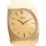 Closeup Photo of a vintage Rolex Geneve Rectangular from the 1960s on a wrist. In yellow gold, 28mm, Manual wind movement, Original golden sigma dial, and Original gold bracelet.