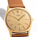 A closeup photo of a vintage Rolex Cellini 3806 Ellipse 18k from 1974 on a wrist in Yellow gold. 32mm, Manual wind movement, Original golden dial and Original hands & crown with cognac brown Leather strap.