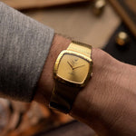 Vintage Rolex Cellini 4084 watch, square  case in 18k yellow gold case, golden dial, manual, gold bracelet on blurred background