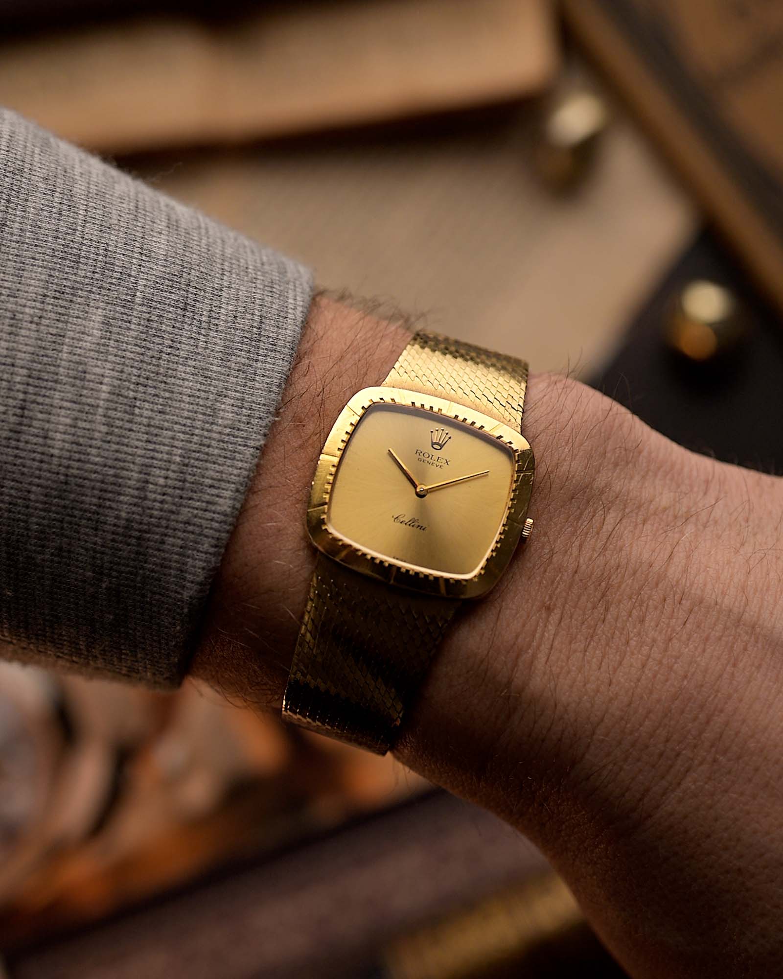 Vintage Rolex Cellini 4084 watch, square  case in 18k yellow gold case, golden dial, manual, gold bracelet on blurred background