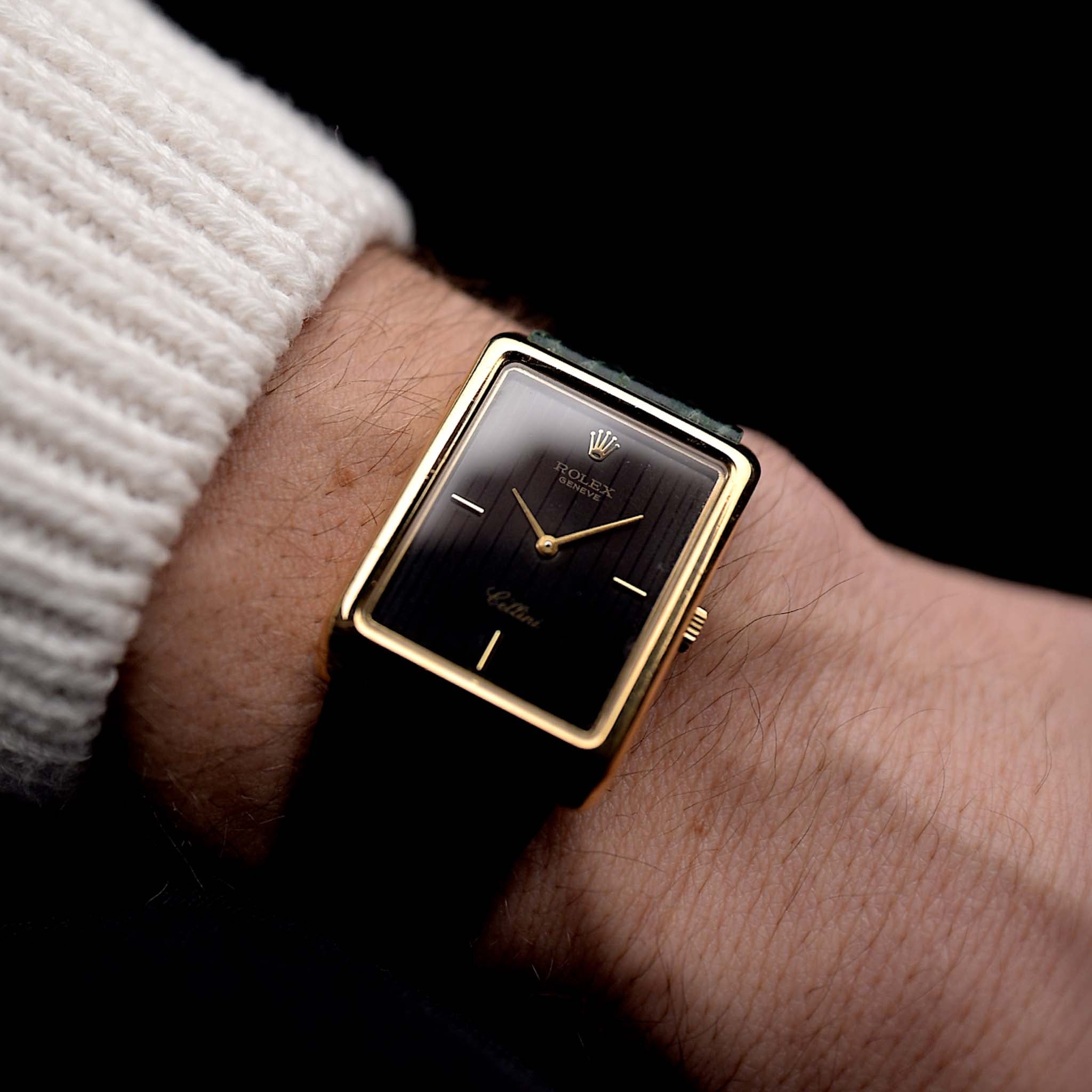 Photo of a Rolex Cellini 4105 Rectangular Black from 1976 on a wrist. 25.5mm  18k yellow gold case with Manual wind movement, Original black tapestry dial and Leather strap.