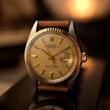 Vintage-Rolex-Datejust-Uhr aus dem Jahr 1972, zweifarbig, mit goldfarbenem Zifferblatt im „Pie-Pan“-Design, 36-mm-Oyster-Gehäuse, auf einer reflektierenden Unterlage.