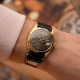 Rolex Day-Date 1803 Vintage watch from 1974, 18k yellow gold, grey pie pan dial, automatic movement, on a wrist on blurred background