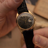 Rolex Day-Date 1803 Vintage watch from 1974, 18k yellow gold, grey pie pan dial, automatic movement, held in a hand.