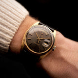 Rolex Day-Date 1803 Vintage watch from 1974, 18k yellow gold, grey pie pan dial, automatic movement, on a wrist on black background