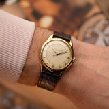 Vacheron Constantin Spillmann Vintage Uhr den 1940er Jahren, 18 Karat Gelbgold, zweifarbiges Zifferblatt in Silber und Champagner, Automatikwerk an einem Handgelenk vor verschwommenem Hintergrund