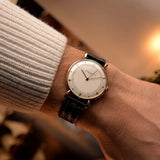 Vintage Vacheron Constantin Teardrop watch in 18k rose gold, white-silver dial, manual Cal. V454, on black strap on a wrist, blurred background