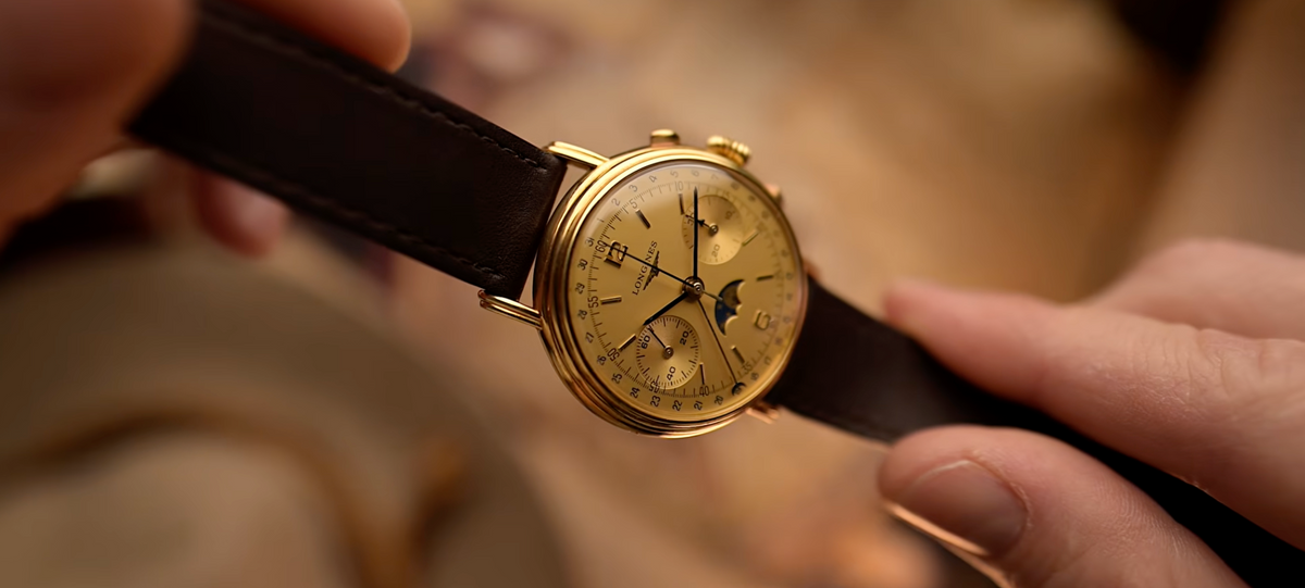 Close-up of a person wearing a gold wristwatch with a dark leather strap.