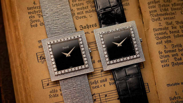 Two silver watches with black faces on an old book