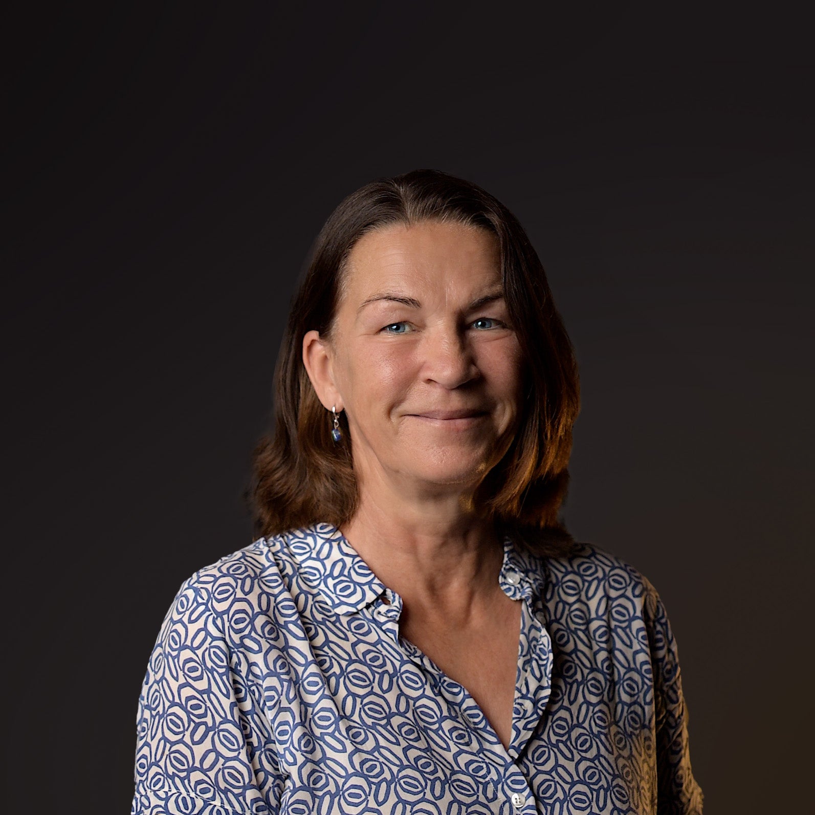 Woman wearing a patterned shirt against a dark background