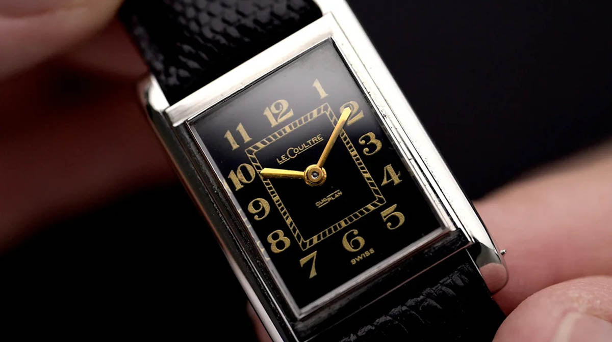 Vintage rectangular LeCoultre watch with black dial and gold details.