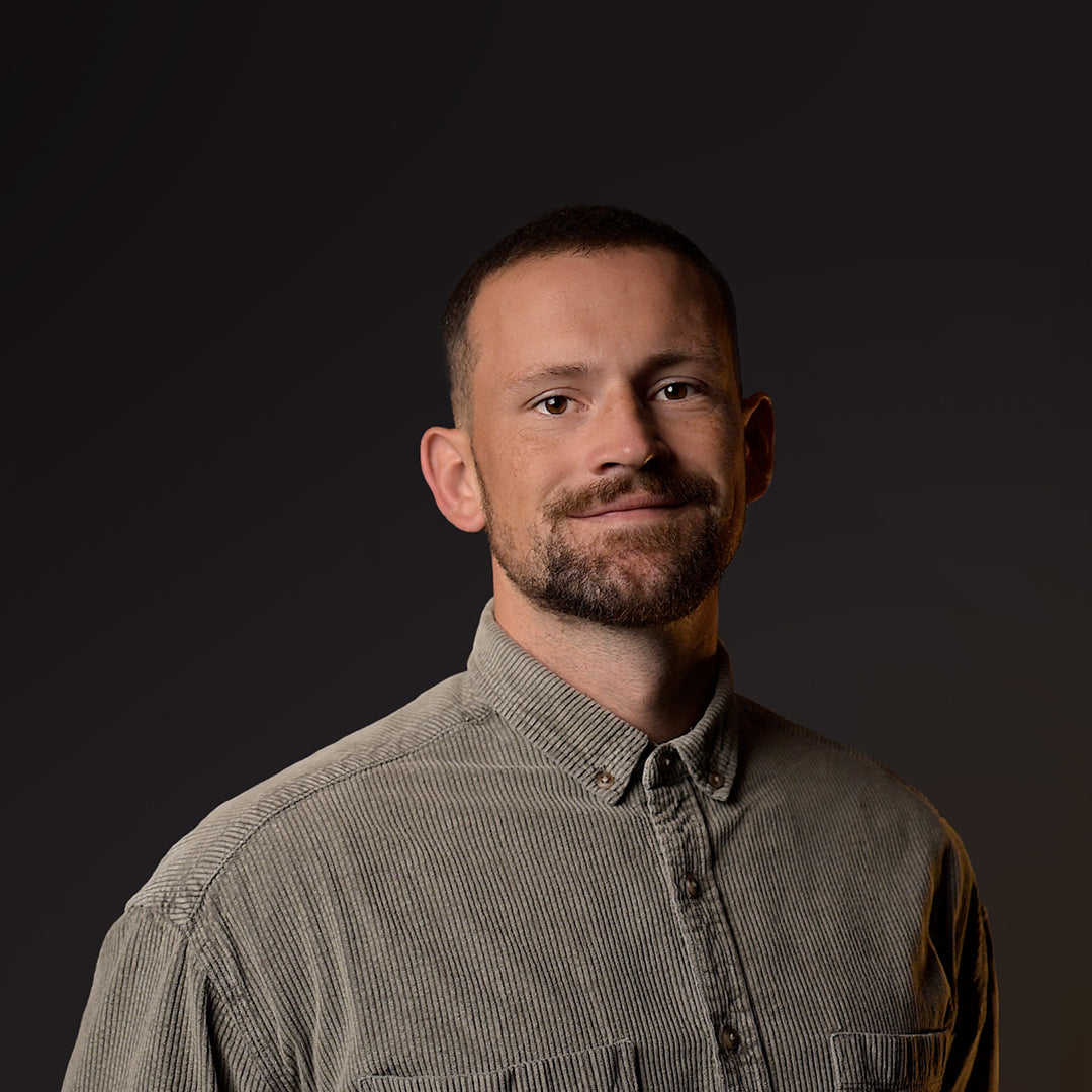 Man wearing a brown corduroy shirt against a dark background