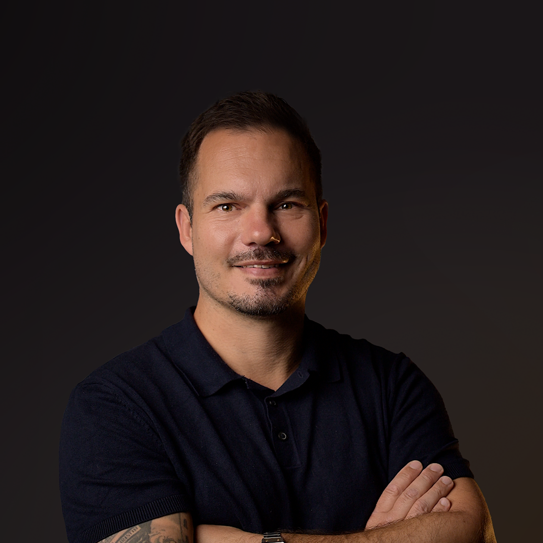Man wearing a dark polo shirt against a dark background