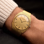 Vintage Watch Vacheron Constantin 7595 C-Shape Automatic Linen from the 1970s on a wrist. 34mm in 18k Yellow Gold with Automatic Caliber K1121, Golden Linen Dial, 18k Yellow Gold Bracelet.