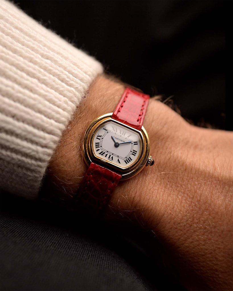 Vintage Cartier Ellipse 67081 Watch 18k from the 1980s on a wrist. 26mm with 18k Yellow Gold case, Manual wind movement, Paris-signed dial, Blued steel hands and Red Leather strap.