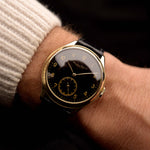 Vintage IWC Pre Hermet watch, in 14k yellow gold, black gilt dial, Cal 83 manual, black leather strap on a wrist on black background, video