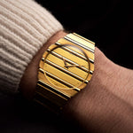 Vintage Piaget Polo 7661 watch from 1980s, 18k gold, gold dial, round case, quartz movement, integrated bracelet on a wrist on black background, video