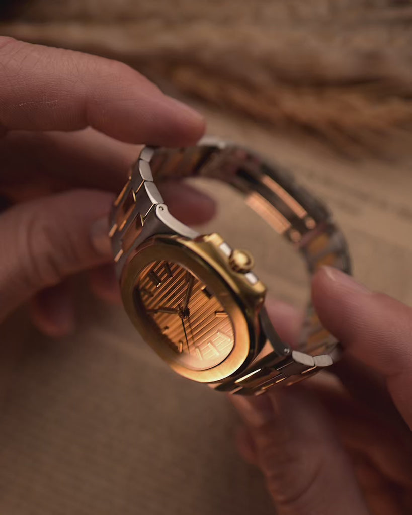 Vintage Patek Philippe Nautilus 3800 watch in two-tone gold and stainless steel, golden ribbed dial, automatic movement, on wrist, blurred background, video of details