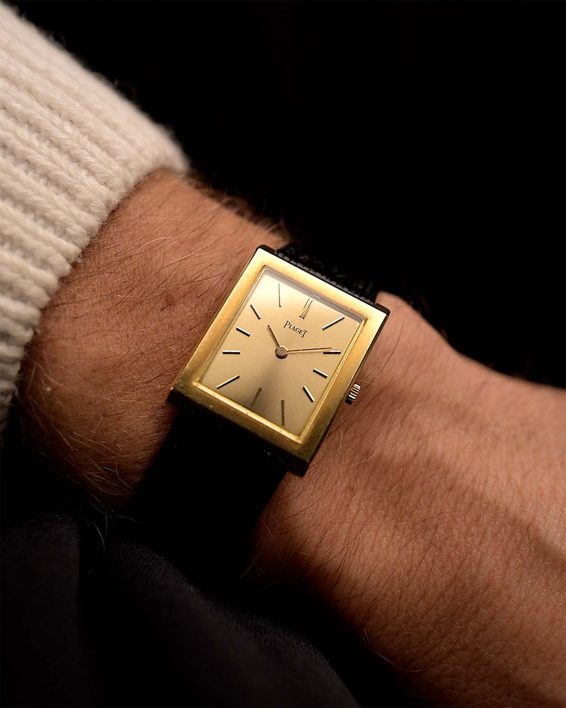 Gold Vintage Piaget 9653 Tank watch on a person's wrist with a dark background.