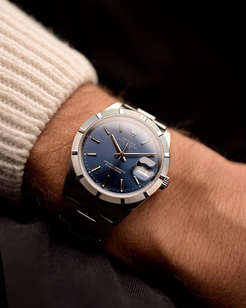 Rolex Oyster Perpetual 15210 Date Blue from 2004 on a wrist on black background. 34mm wide, Stainless Steel, Automatic Caliber 3135, Flawless Blue Dial and Rolex Oyster Bracelet.