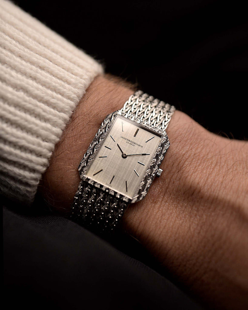 Vintage Vacheron Constantin 7457 Rectangular watch from the 1970s on a wrist on black background. 25mm wide, 18k White Gold, Manual wind Caliber 1003, Flawless silver linen dial and Braided bracelet.