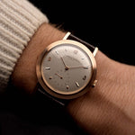 Vintage Vacheron Constantin Dress watch from 1940s, 18k rose gold, silver dial, manual movement, lizard embossed strap on a wrist on black background, video