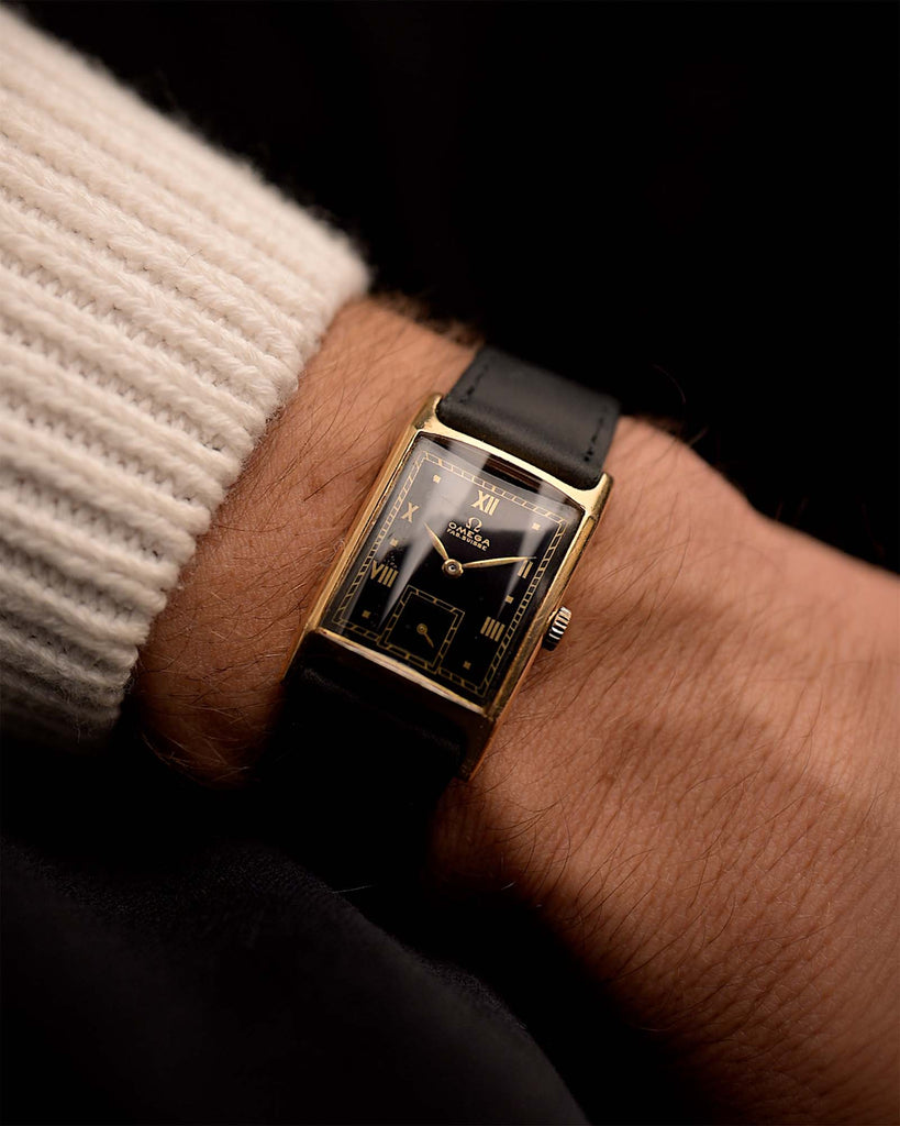 Vintage Omega Tank Gilt watch Roman from 1944 on a wrist. 18mm wide with 18k Rose Gold Case, Manual Wind Movement, Black Gilt Dial, Roman Numerals and Black Leather Strap.