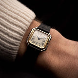 Vintage Cartier Ceinture Uhr aus den 1980er Jahren, zweifarbiges Gold, weißes Zifferblatt, quadratisches Gehäuse, Handaufzug, an einem Handgelenk auf schwarzem Hintergrund