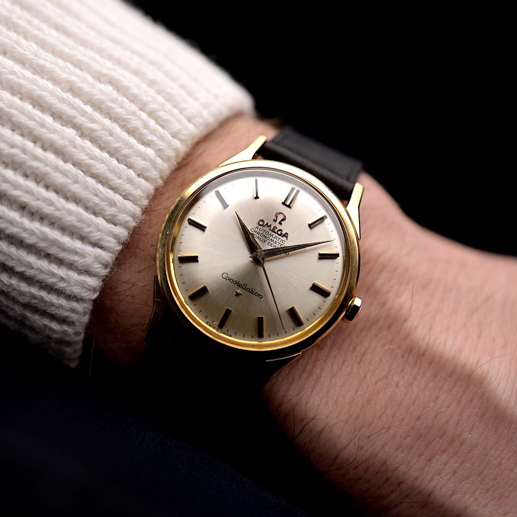 Foto einer Vintage Omega Constellation 167005 von 1963 an einem Handgelenk. In 18k Gelbgold, 34mm, Automatik-Chronometer Kaliber 551 und Original silbernes Tortenboden-Zifferblatt.