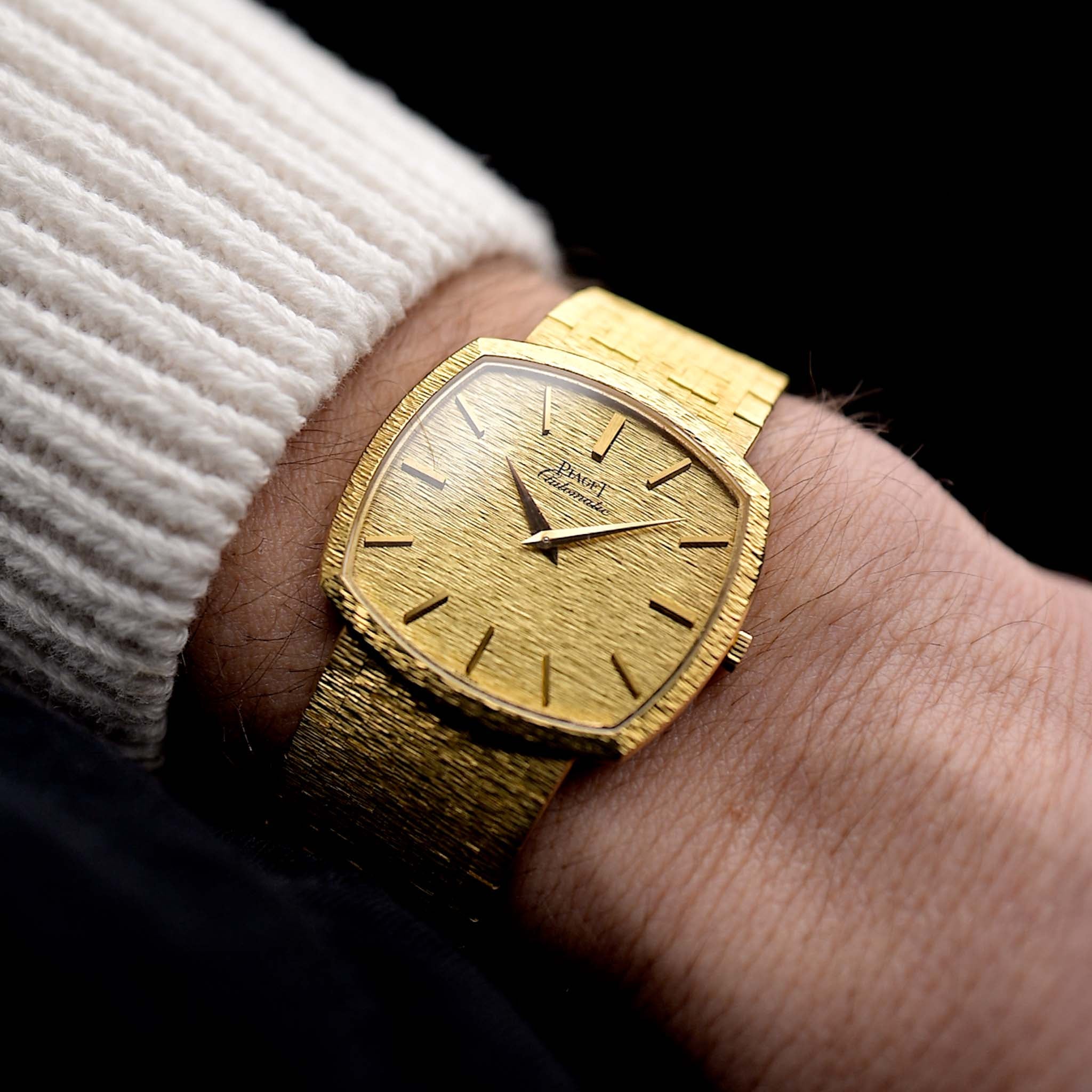 Foto einer Piaget TV 12401 Automatic 18k aus den 1970er Jahren an einem Handgelenk. 32,5 mm großes Gehäuse aus 18k Gelbgold mit Automatikwerk, originalem, makellosem, gehämmertem Zifferblatt und integriertem 18k-Armband.