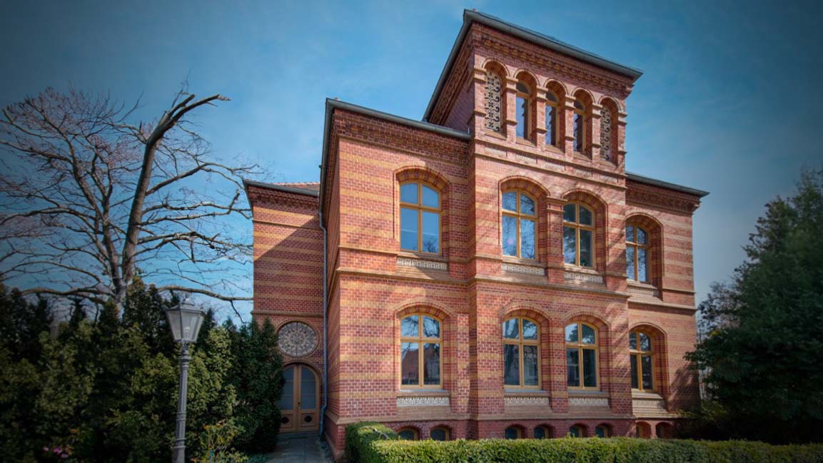 Backsteingebäude mit Rundbogenfenstern und Turm.