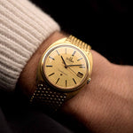 Vintage Omega Constellation 168009 C-Shape Uhr 1966, 14k Gelbgold, Leinenzifferblatt, Goldarmband am Handgelenk einer Person mit dunklem Hintergrund, Video