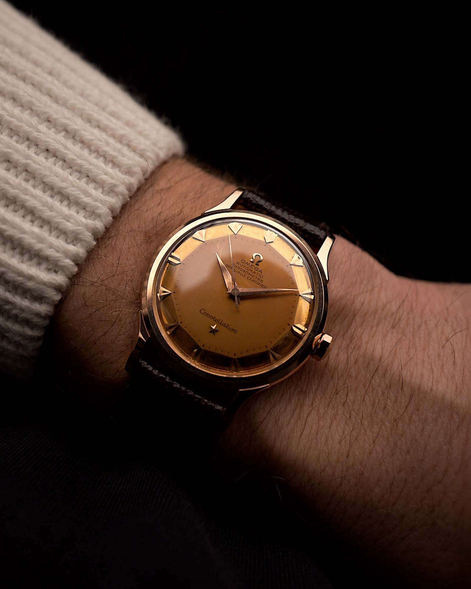 Vintage Omega Constellation 2700SC Uhr aus 18 Karat Roségold, rundes Gehäuse, rosafarbenes Zifferblatt, Stoßsicherung, Eidechsenlederarmband an einem Handgelenk vor schwarzem Hintergrund, Video