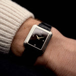 Piaget Protocole 74101 Vintage Uhr aus den 1980er Jahren an einem Handgelenk auf schwarzem Hintergrund. 26 mm breit, Gehäuse aus 18 Karat Weißgold, makelloses Onyx-Zifferblatt mit 4 Diamanten, Quarzwerk und schwarzes Original-Lederarmband.