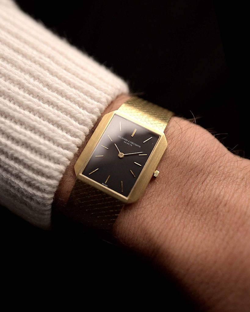 Vintage Vacheron Constantin 7457 Rectangular aus den 1970er Jahren an einem Handgelenk. 25 mm aus 18 Karat Gelbgold mit schwarzem Original-Zifferblatt, Handaufzug Kal. 1003 und Goldarmband.
