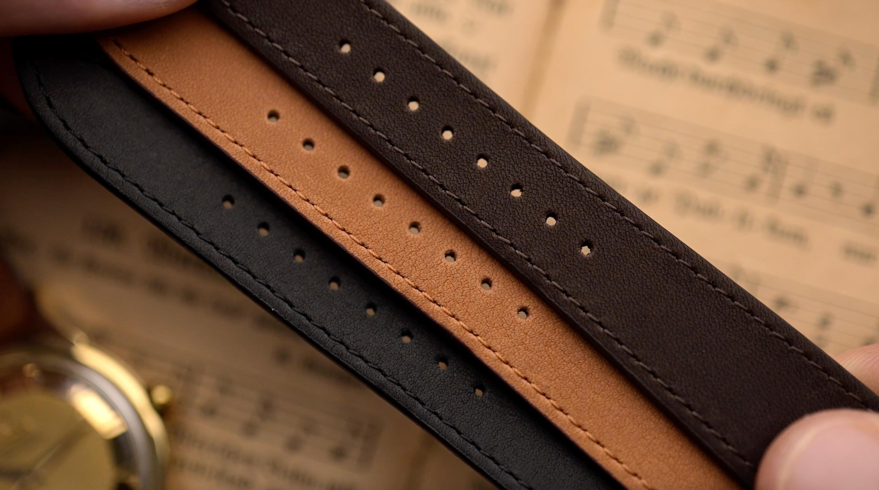 Nahaufnahme von drei Lederarmbändern in schwarz, braun und congnac, jeweils mit gestanzten Löchern.