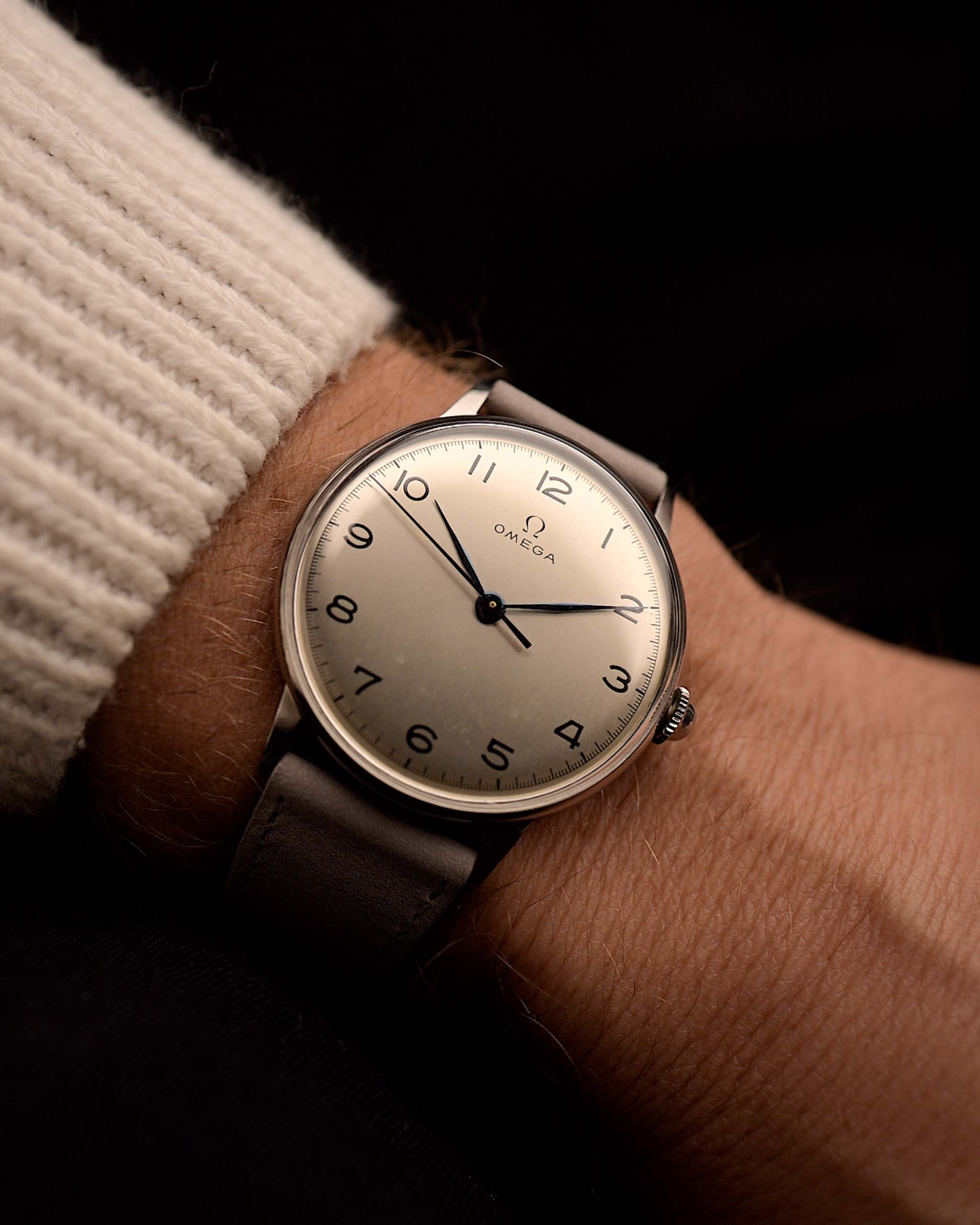 Reloj vintage Omega 2325 Jumbo Leaf, esfera plateada, caja de acero inoxidable, movimiento de cuerda manual, correa de piel gris, en la muñeca, fondo negro