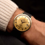 Reloj Vintage Omega Constellation 168004 Onyx 18k de 1963 en muñeca. 35,5 mm con caja de oro amarillo de 18 quilates, cronómetro automático Calibre 561, esfera dorada impecable y correa de piel.