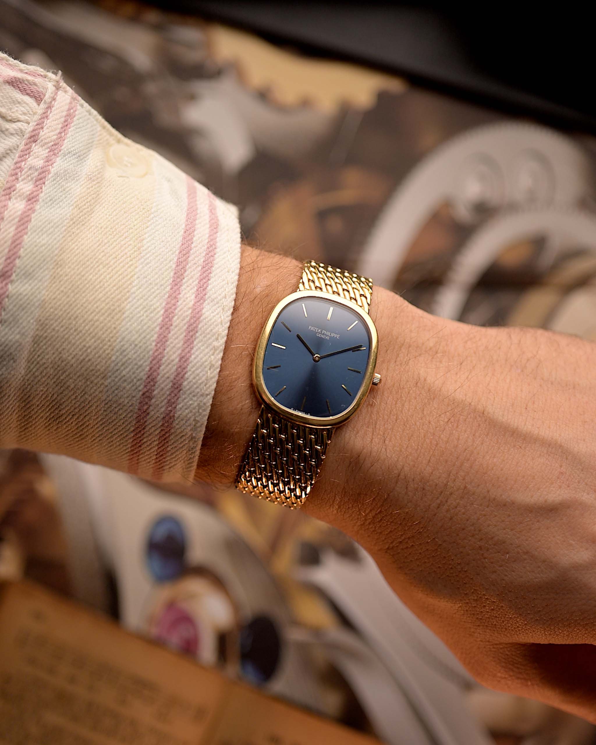Patek Philippe 3738 Ellipse Jumbo Vintage Watch from the 1980s on a wrist on a blurred background. 31mm wide with 18k Yellow Gold Case, Automatic Caliber 240, Flawless Blue Sunburst Sigma Dial and Yellow Gold Bracelet.