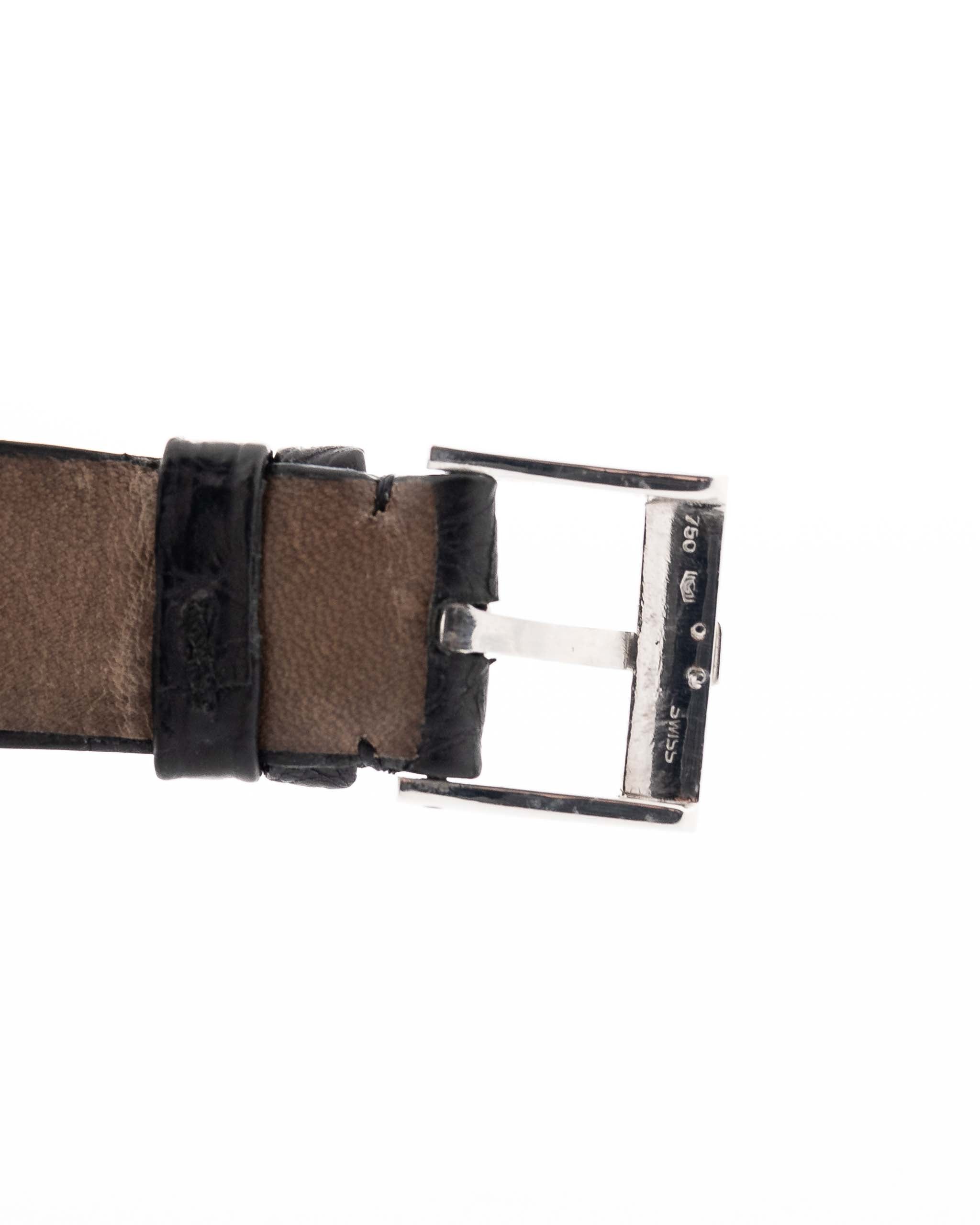 Foto de cerca de un Piaget Protocole 927 de oro blanco de 18 quilates de la década de 1970. 25 mm en oro blanco de 18 quilates con movimiento de cuerda manual, esfera plateada motivo sol y correa original de piel negra.