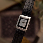 Reloj Piaget Protocole 9151 vintage, oro blanco 18 quilates, esfera ónice, forma tanque, movimiento Calibre 9P, pulsera de piel, sobre fondo difuminado