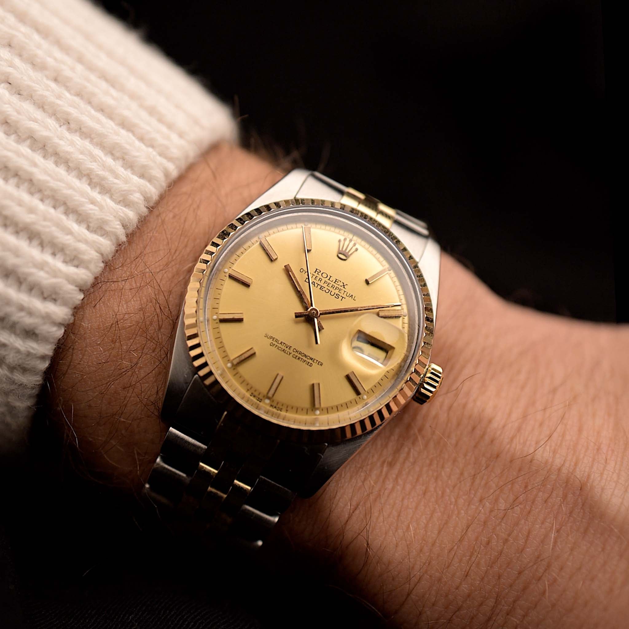Rolex Datejust 1601 Two Tone de 1970 en muñeca sobre fondo negro. 36 mm de ancho en oro bicolor/acero inoxidable con calibre Rolex 1570, esfera de oro pie pan impecable y brazalete Jubilee bicolor.
