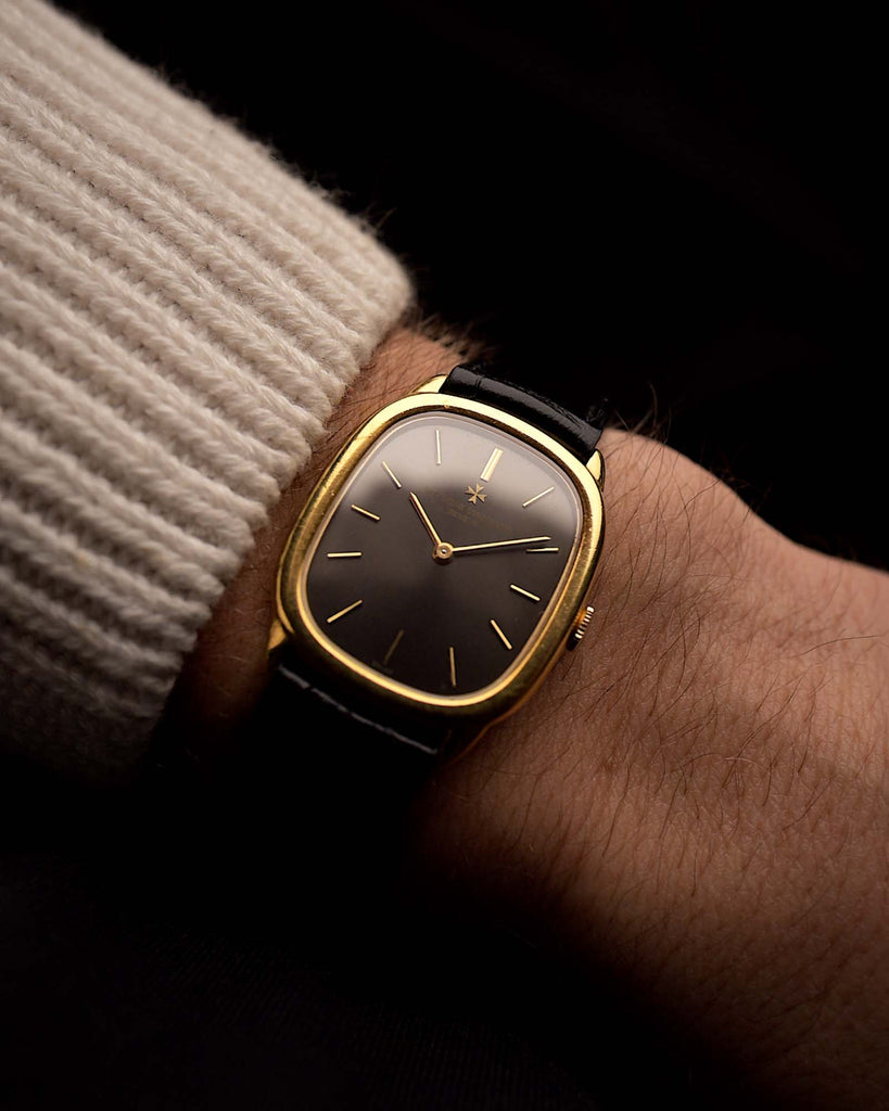 Reloj vintage Vacheron Constantin 39007 Ellipse en oro de 18 quilates, caja elíptica, esfera gris, cuerda manual, correa de cuero negro en una muñeca sobre fondo negro, vídeo.