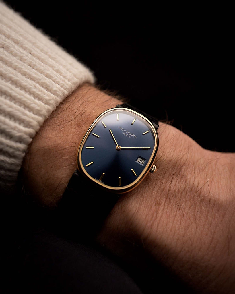 Reloj vintage Patek Philippe Ellipse de la década de 1980, oro de 18 quilates, esfera azul con efecto rayos de sol, movimiento de cuarzo, correa de cuero en una muñeca sobre fondo negro, vídeo.