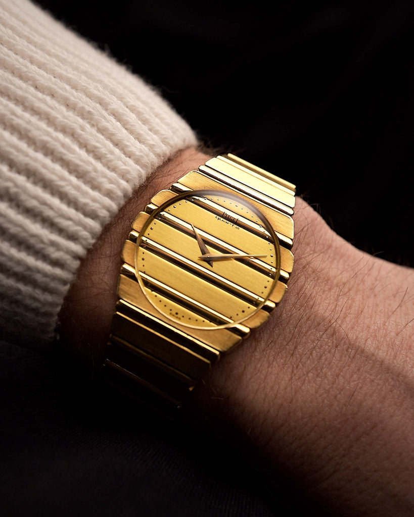 Reloj Piaget Polo 7661 vintage de la década de 1980, oro de 18 quilates, esfera dorada, caja redonda, movimiento de cuarzo, brazalete integrado en una muñeca sobre fondo negro, vídeo.